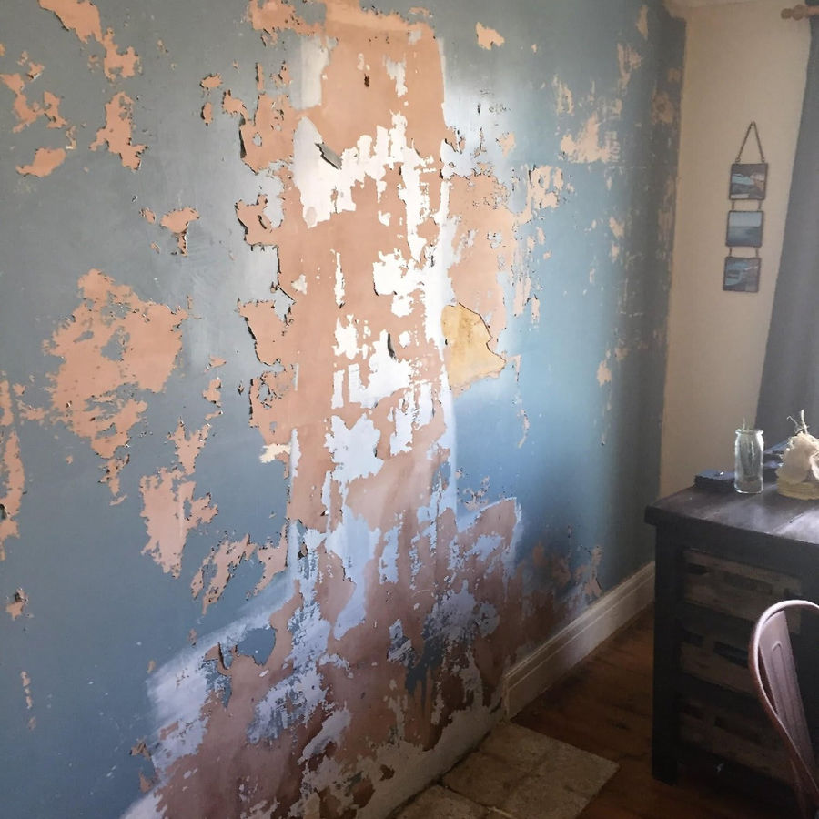 Peeling paint on a damp wall before treatment